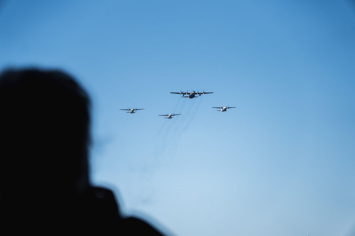 travel photo of polish military parade in warsaw, poland with 4 planes flying past as a child silhouette looks on