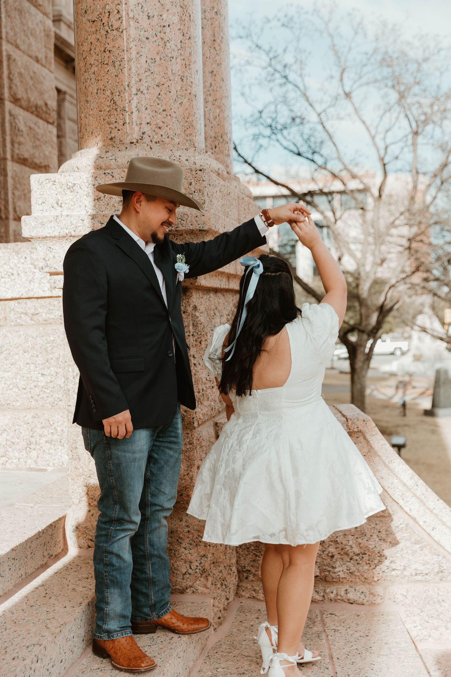 Dancing couple in wedding attire on stone steps of historic building.
