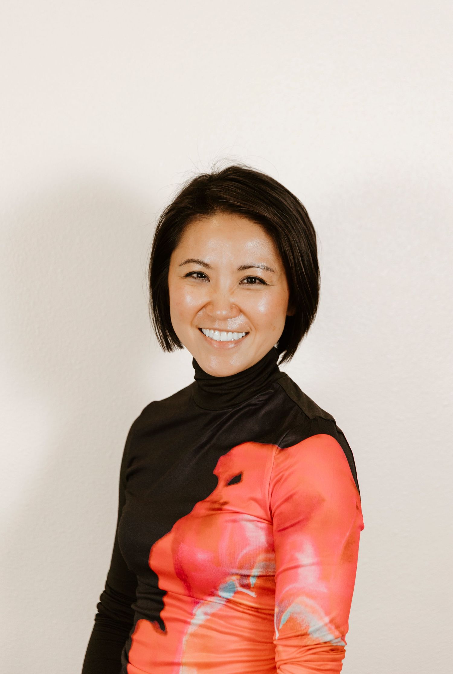 Studio portrait showing person in black top with bright red sleeve detail.