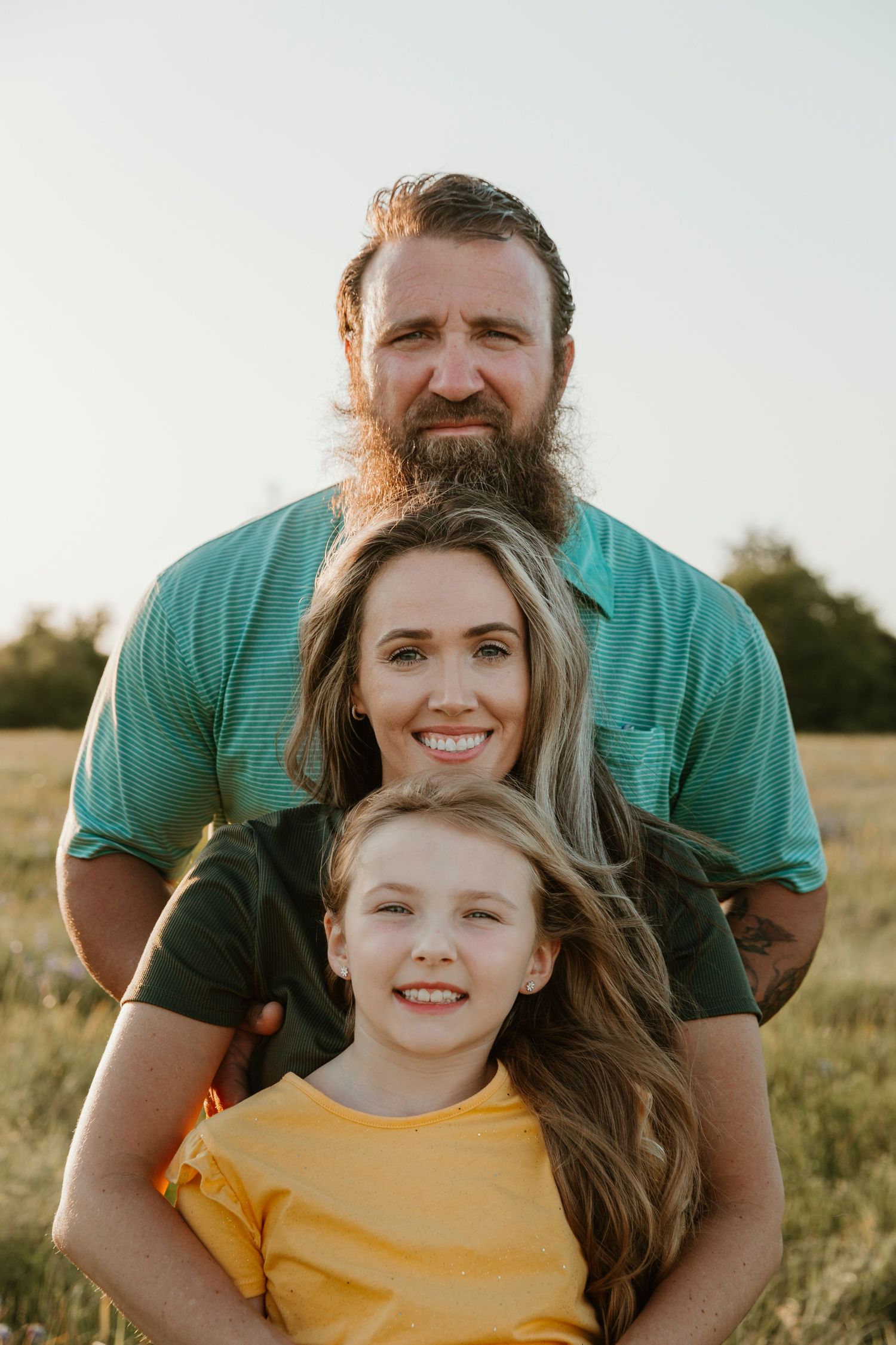 Family portrait taken in a golden meadow during sunset.