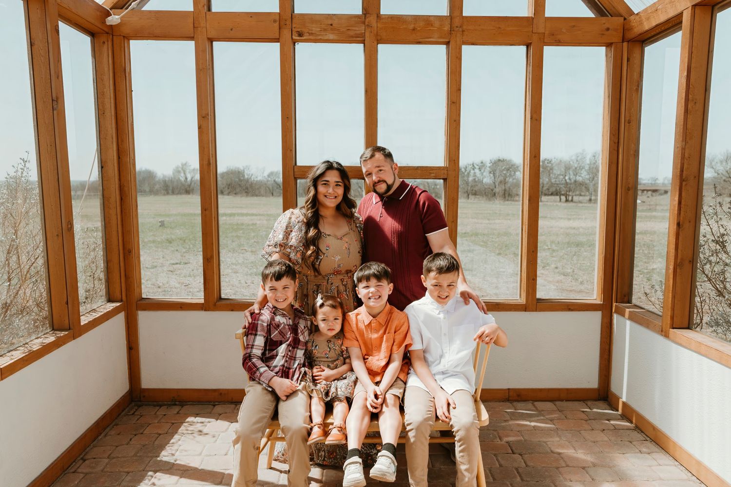 Family photo session in rustic sunroom with wooden beams.
