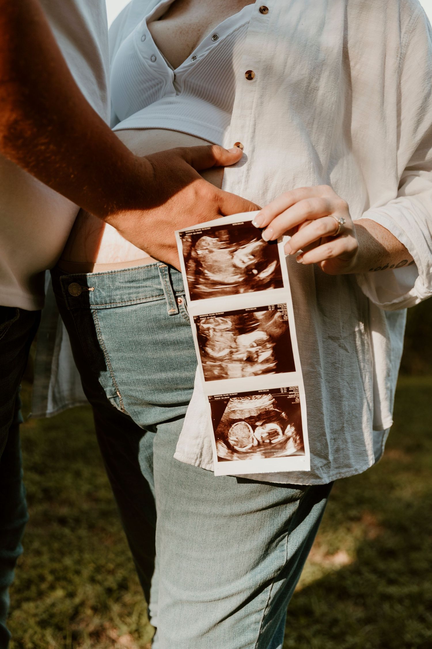 Close-up of hands holding ultrasound photos during a pregnancy announcement session.
