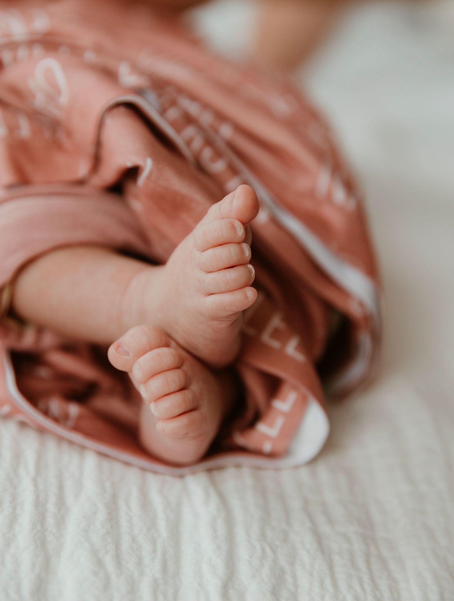 Macro shot of baby feet against coral colored fabric.