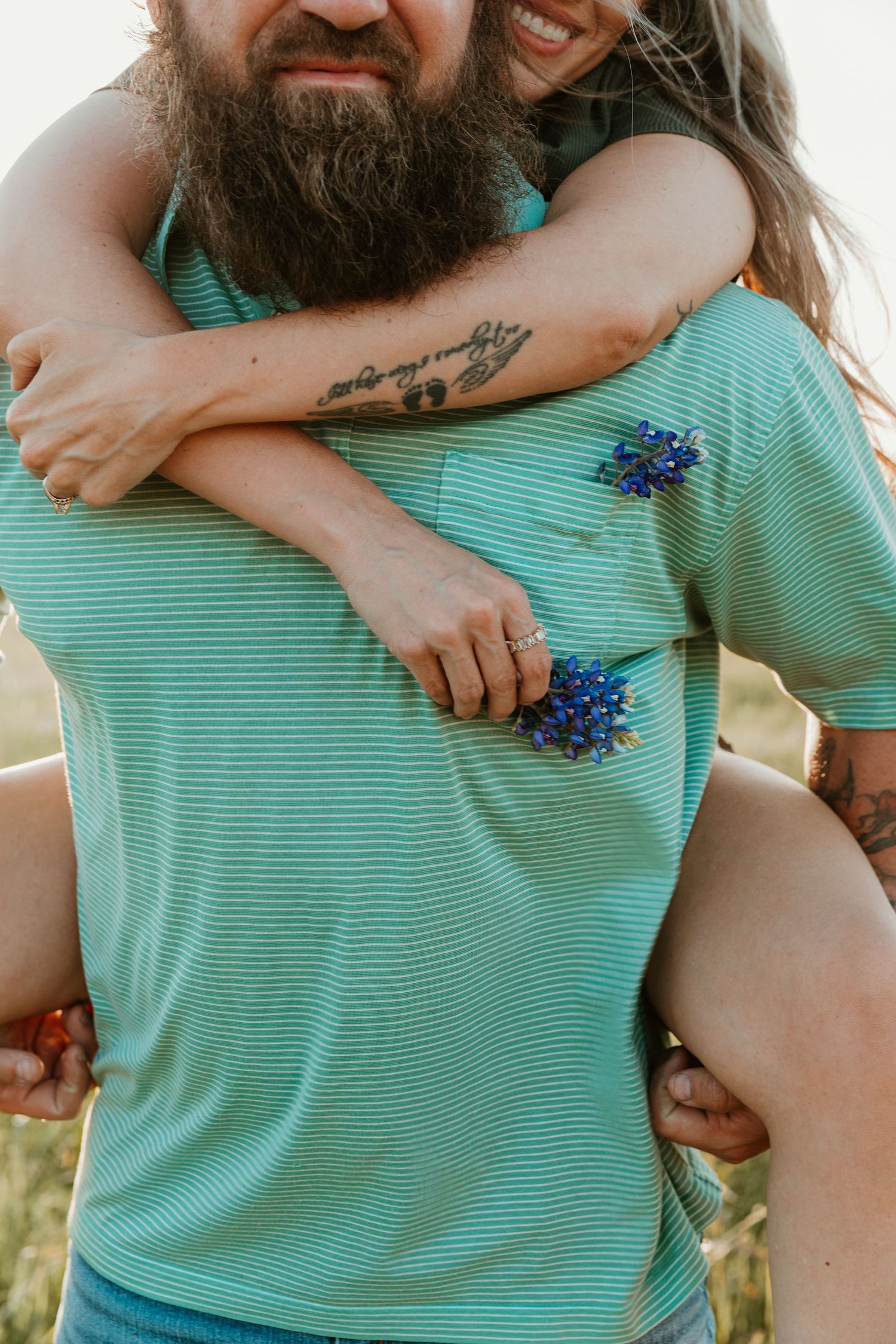 Close-up shots of a couple embracing in a meadow wearing turquoise and holding bluebonnets.