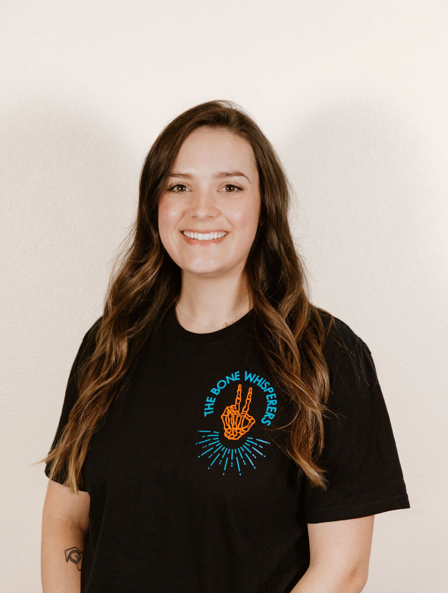 Studio headshot of person in black t-shirt with turquoise embroidered design.