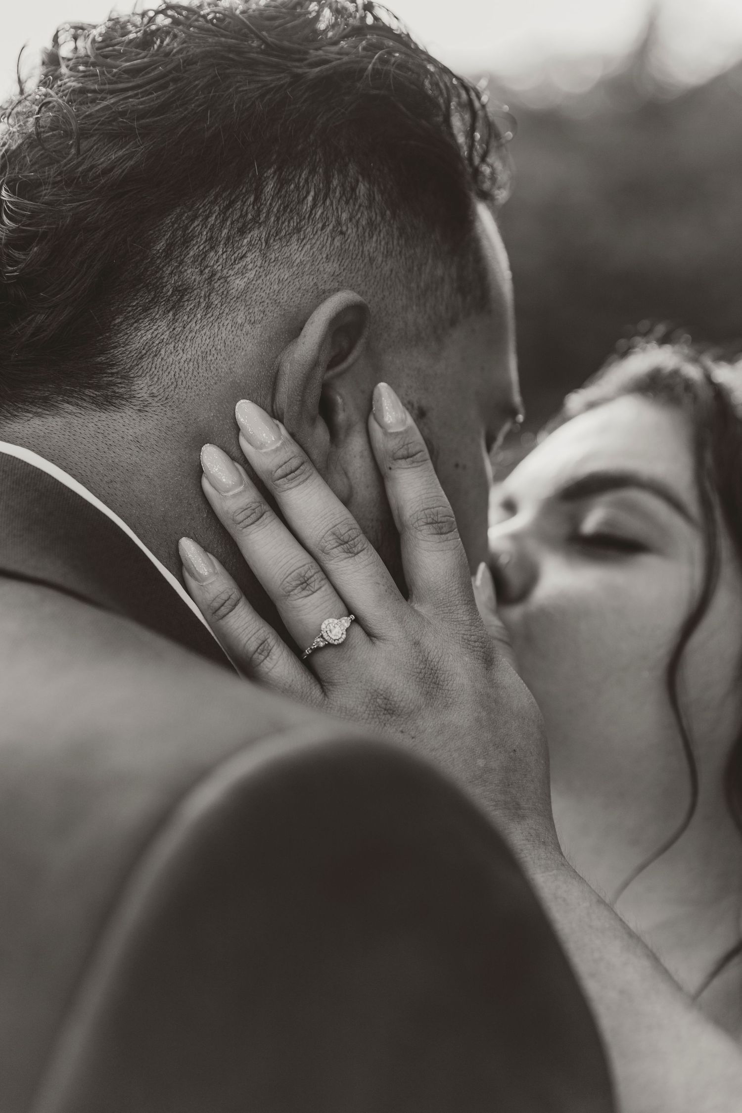 Intimate black and white photo of a romantic wedding moment with bride's hand on groom's face.