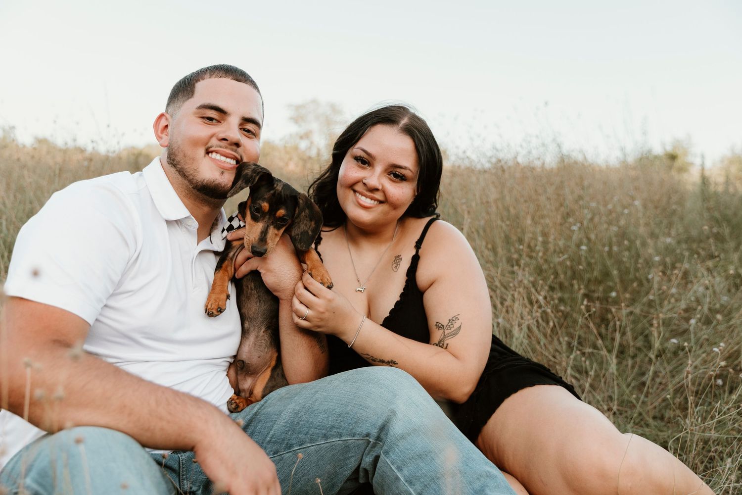 Joyful couple shares loving laughs and tender moments in an outdoor field during golden hour sunset.