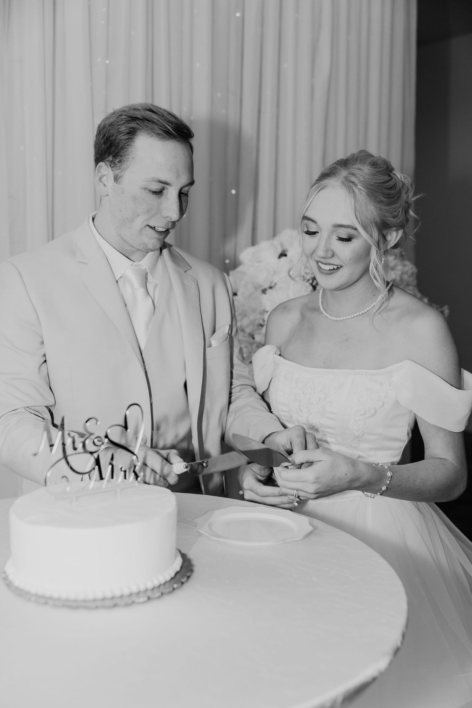 A couple cuts their white wedding cake together during their reception celebration.