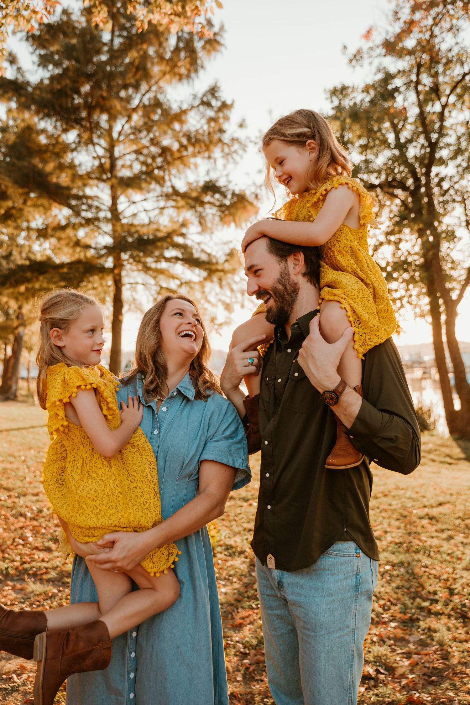 Family shares joyful moments together during golden hour photoshoot in autumn leaves.