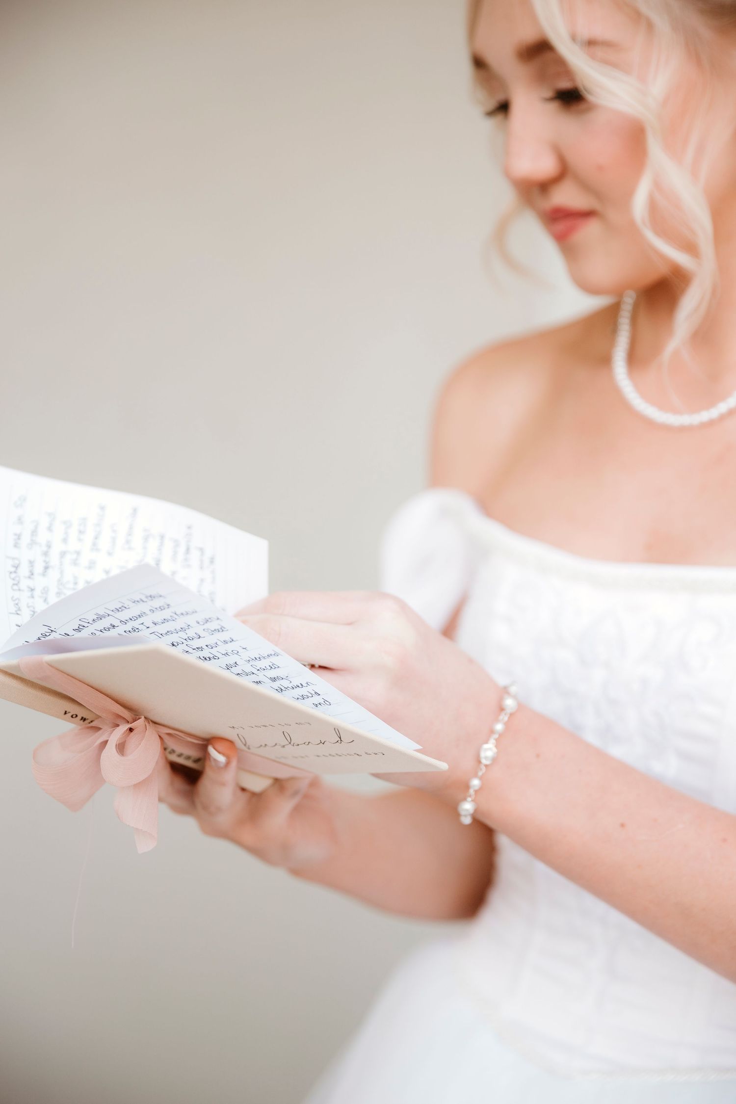 A bride in a white dress reads from handwritten papers, likely wedding vows.