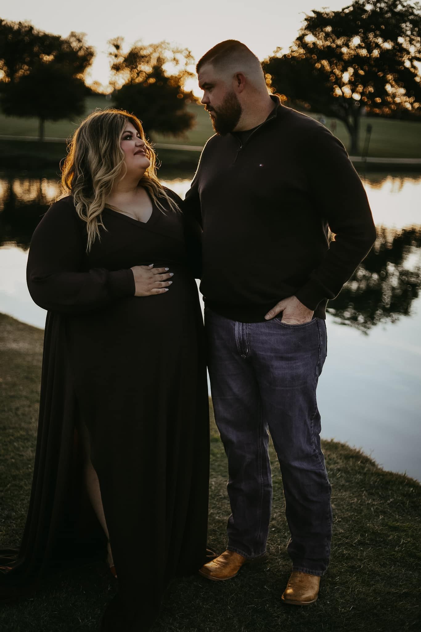 Romantic sunset photoshoot by a lake with couple in dark clothing.
