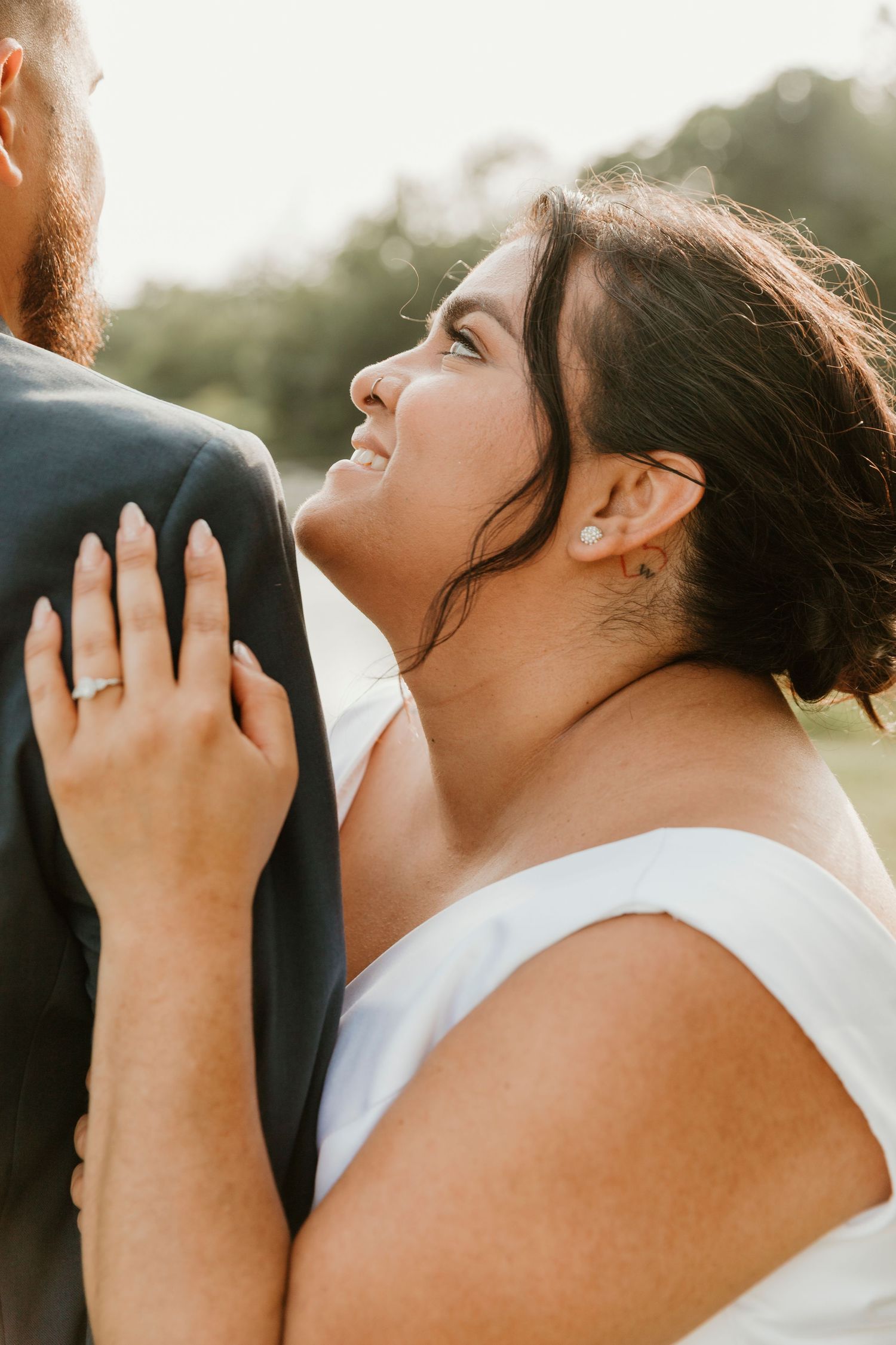 Sun-lit wedding portrait showing intimate moment between newlyweds.