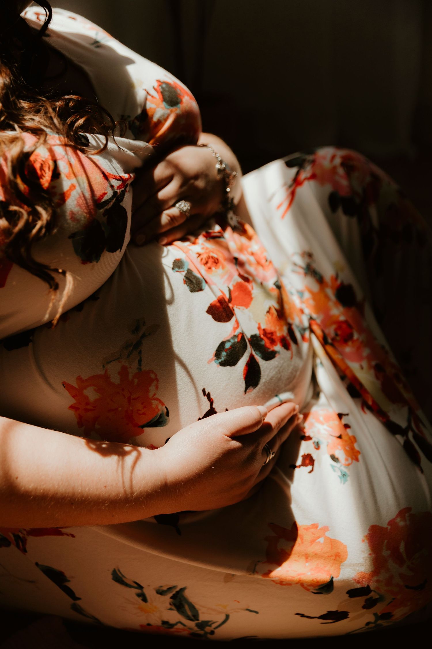 Artistic portrait showing flowing floral dress fabric in moody lighting.