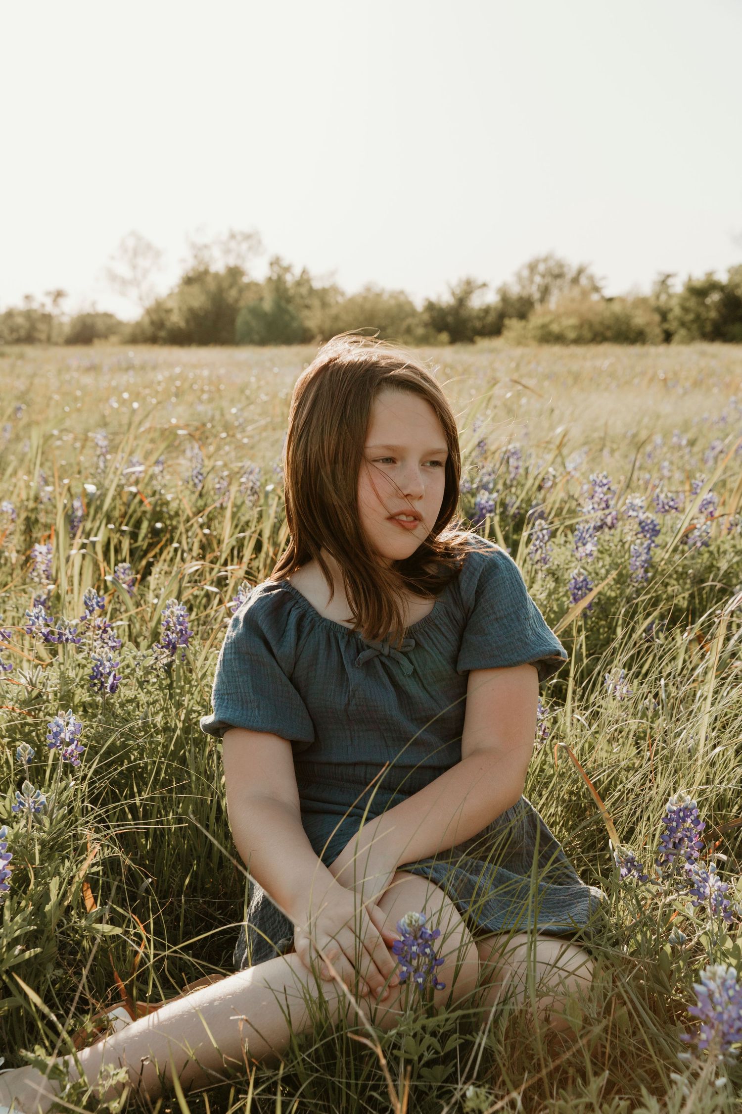Candid portrait in field with purple wildflowers and natural sunset lighting.