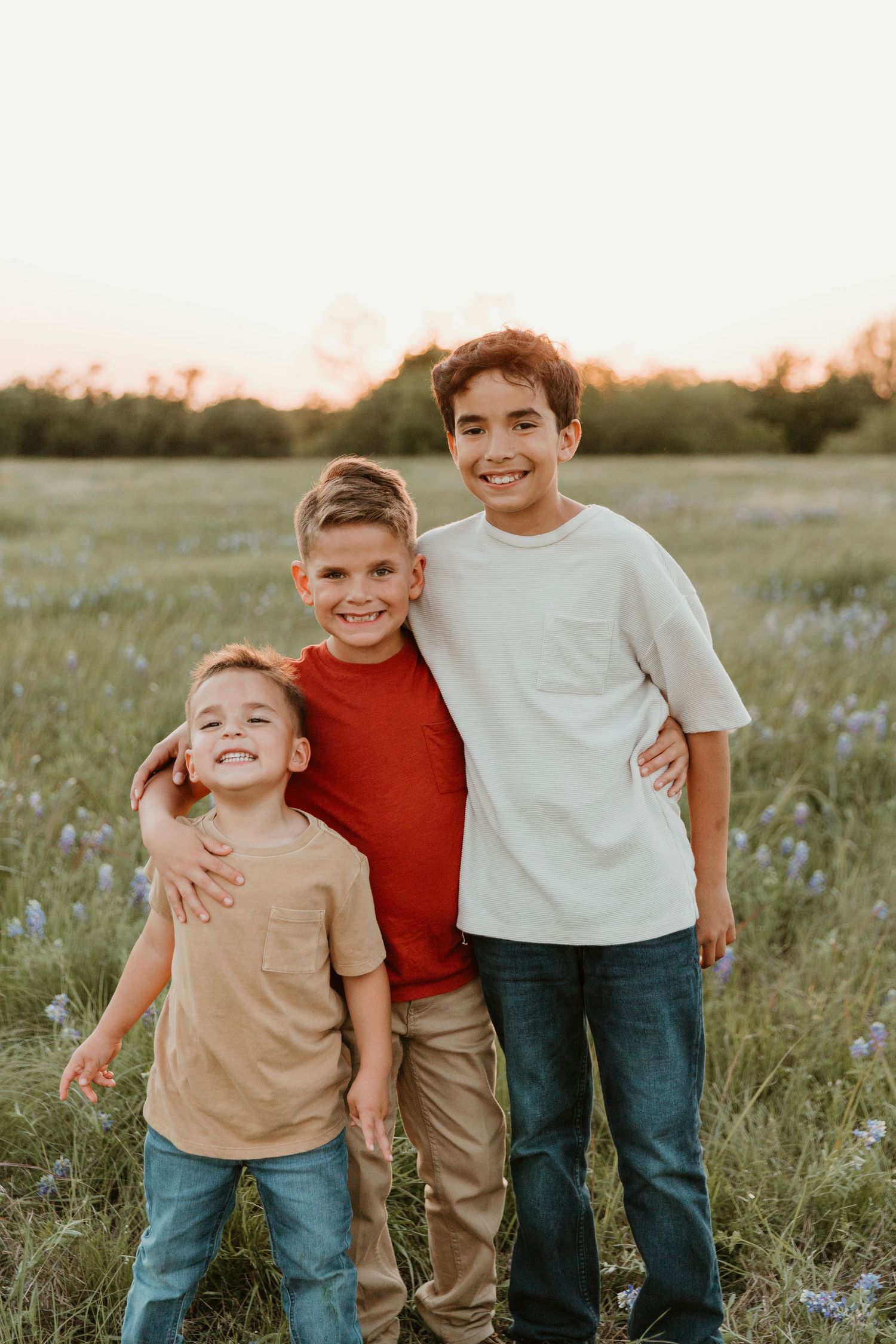 Siblings sharing joyful moments together in a field during golden hour.
