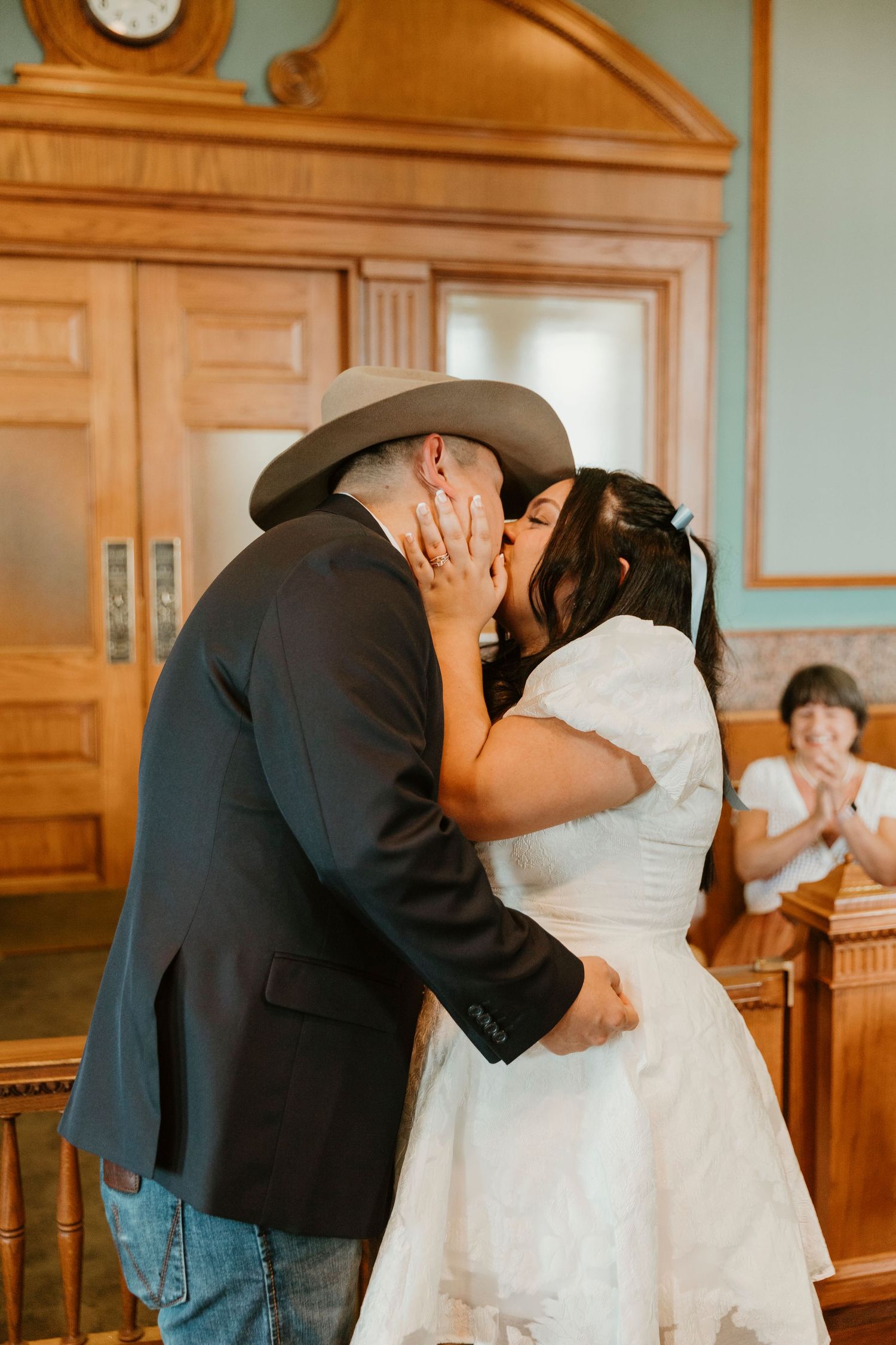 Wedding ceremony kiss captured in a courthouse with wooden details and classic architecture.