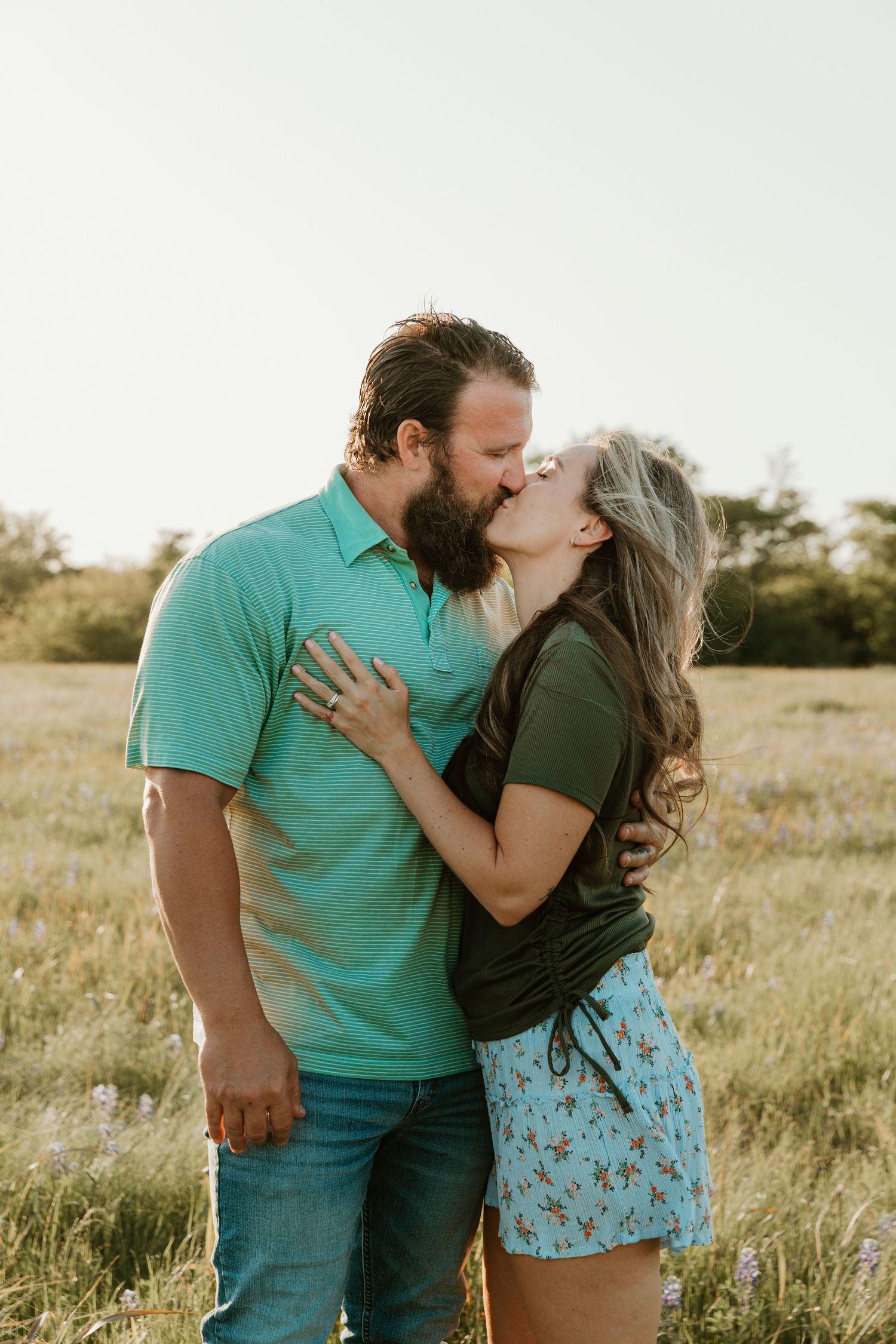 Couple sharing a romantic kiss in a sunlit field.