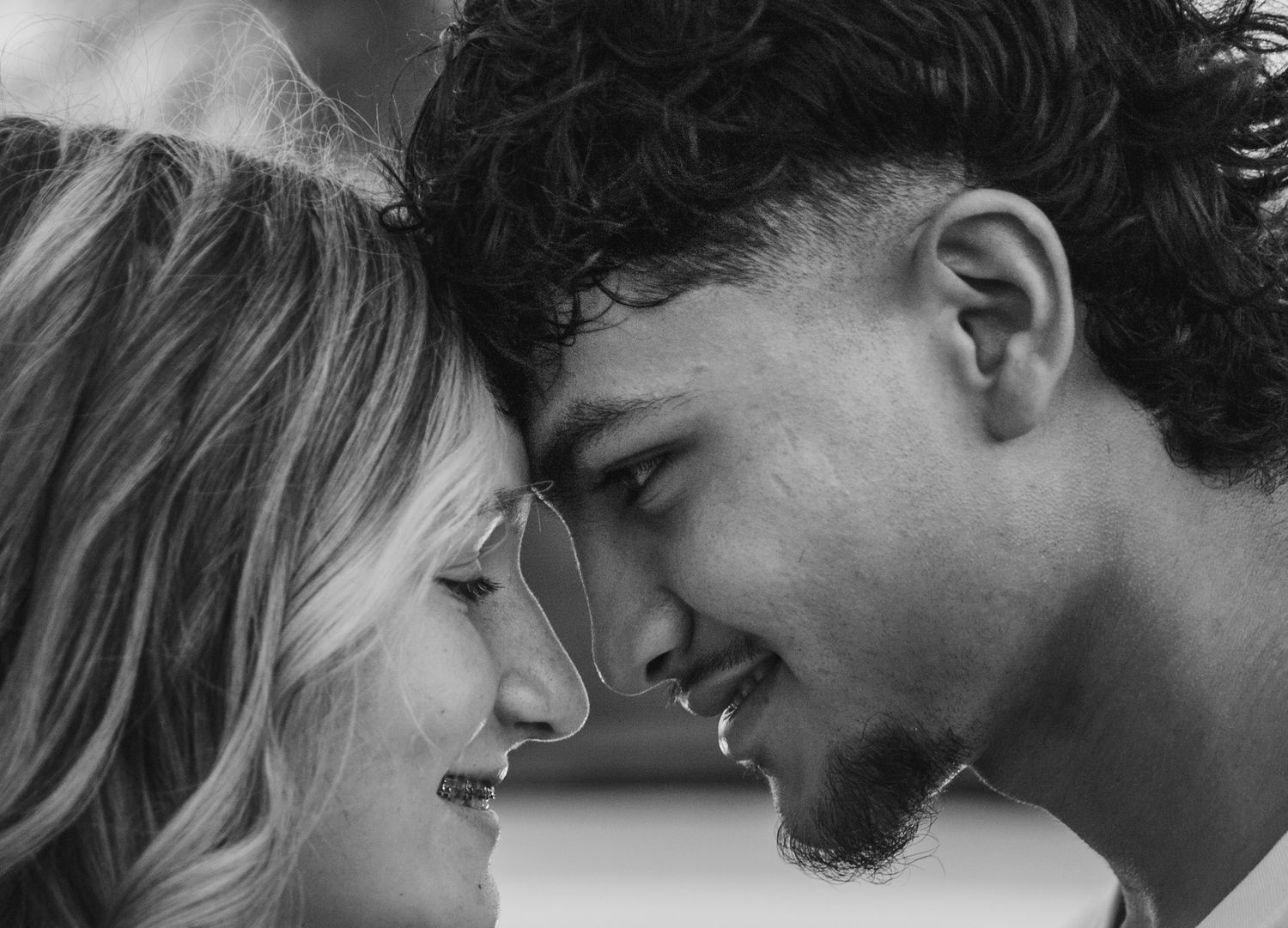 Close up black and white portrait of a couple sharing an intimate moment with their foreheads touching.