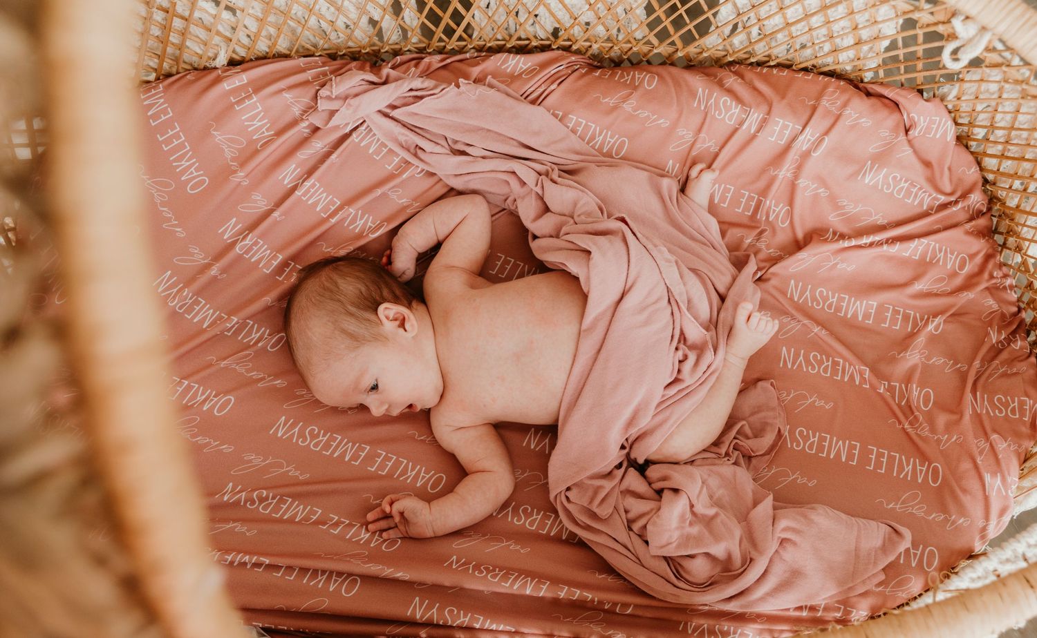 Overhead view of sleeping newborn on coral bedding.