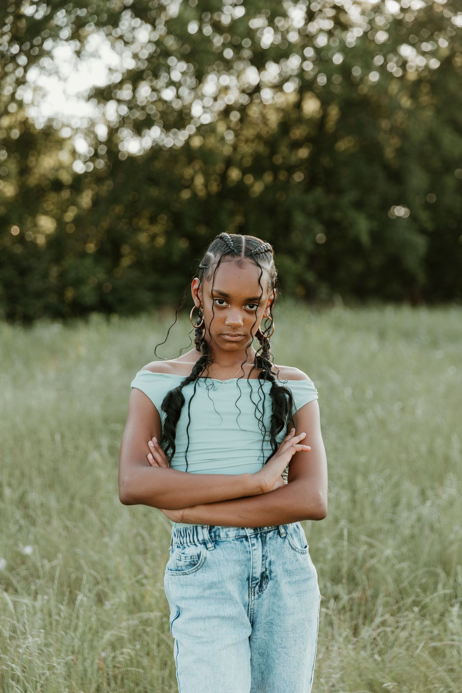 A joyful figure in light blue top and denim overalls poses playfully in a sunlit meadow.