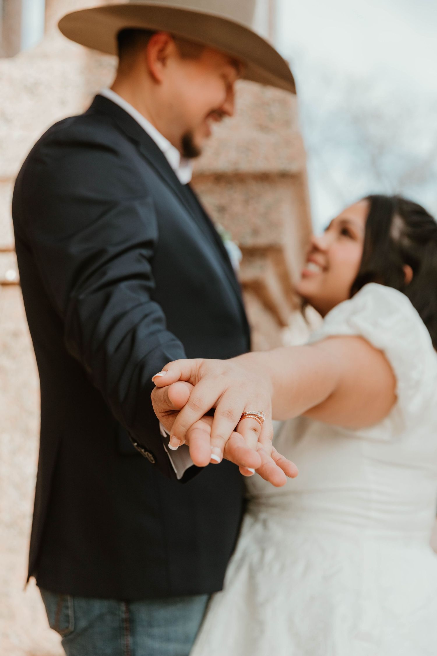 A tender moment between newlyweds as they dance, with the groom wearing a cowboy hat and suit.
