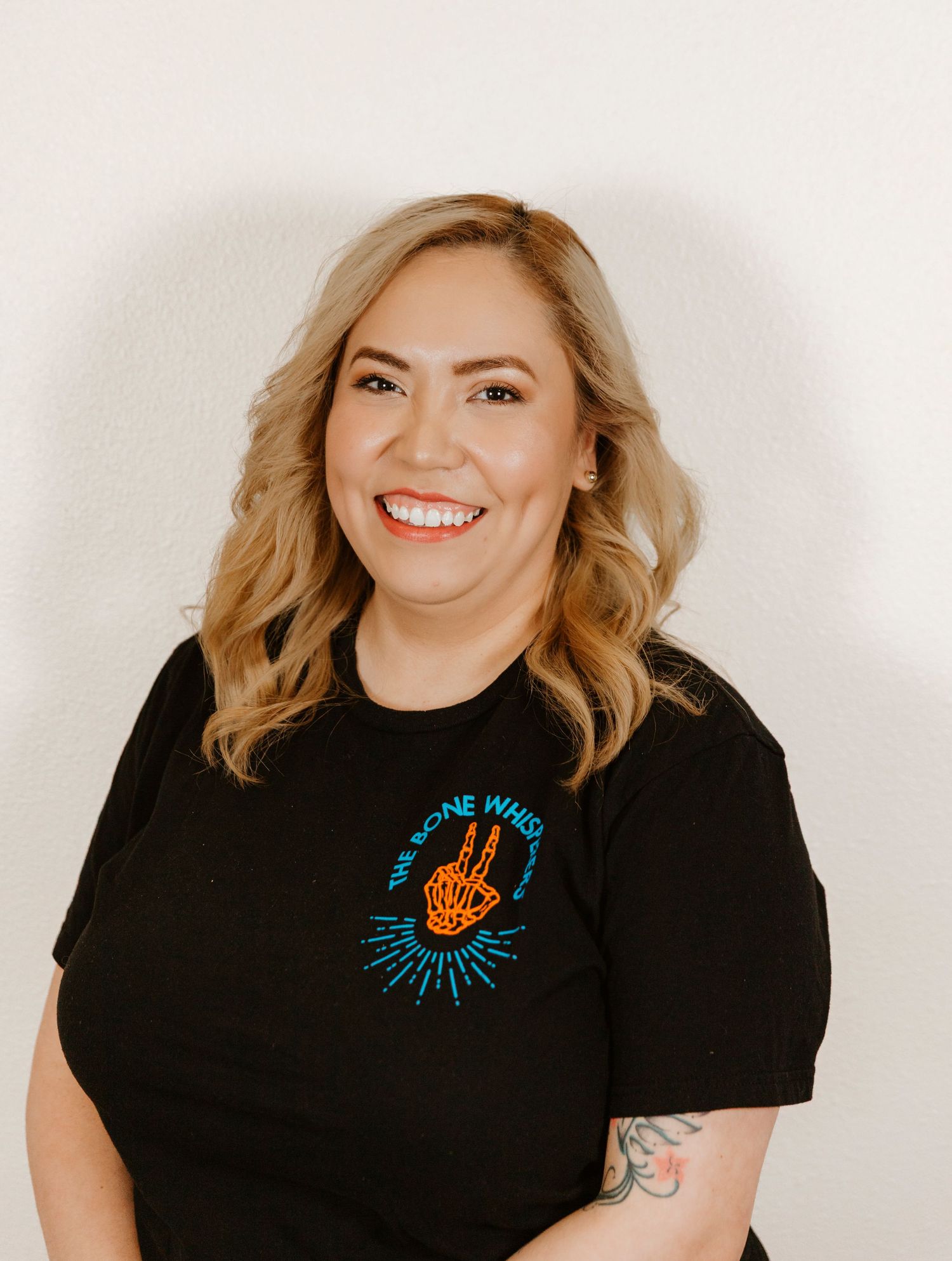 Professional portrait of person in black shirt with embroidered blue design.