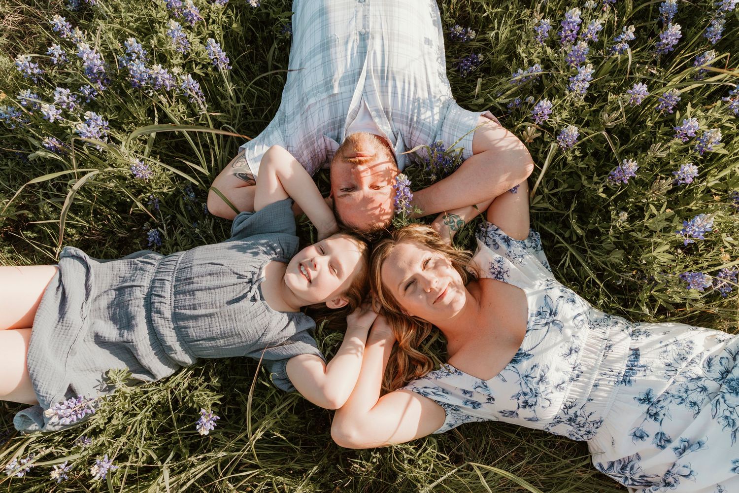 Family relaxing together in wildflower field during sunset photo session.