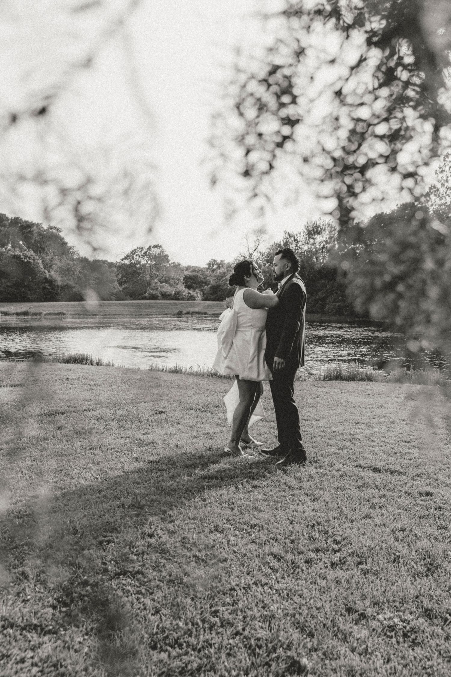 Black and white wedding photo of couple embracing in an open field.