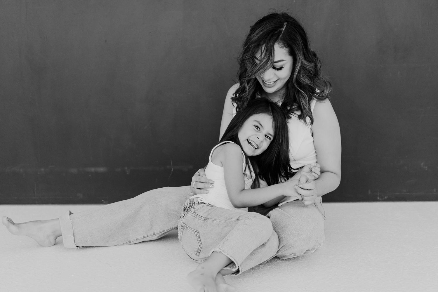 Black and white studio portrait showing tender moment between parent and child.