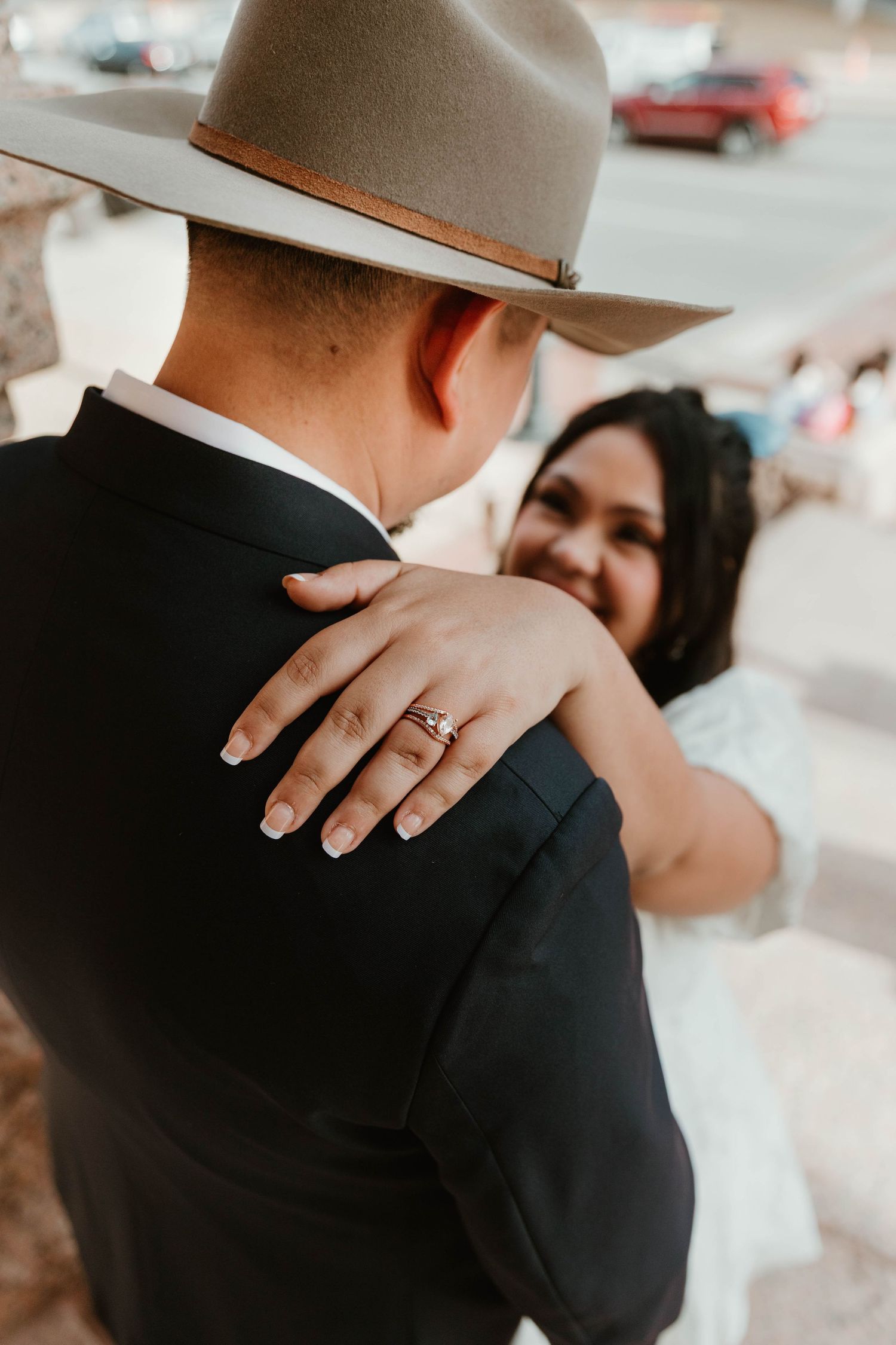 Close-up detail shot of hands and western attire during a romantic moment.