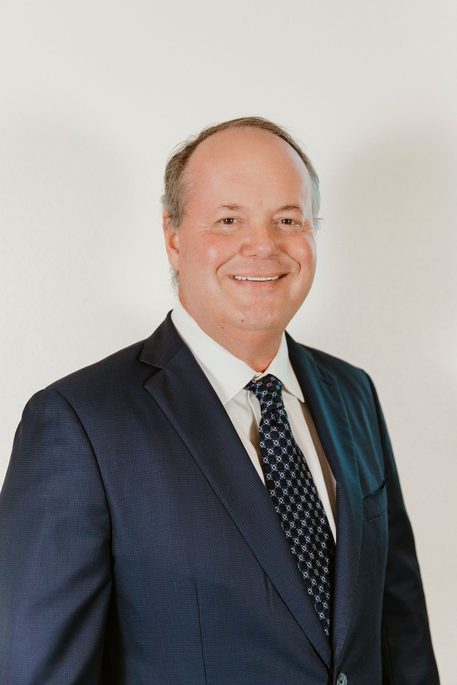 Professional headshots of businessman in navy pinstripe suit and polka dot tie.