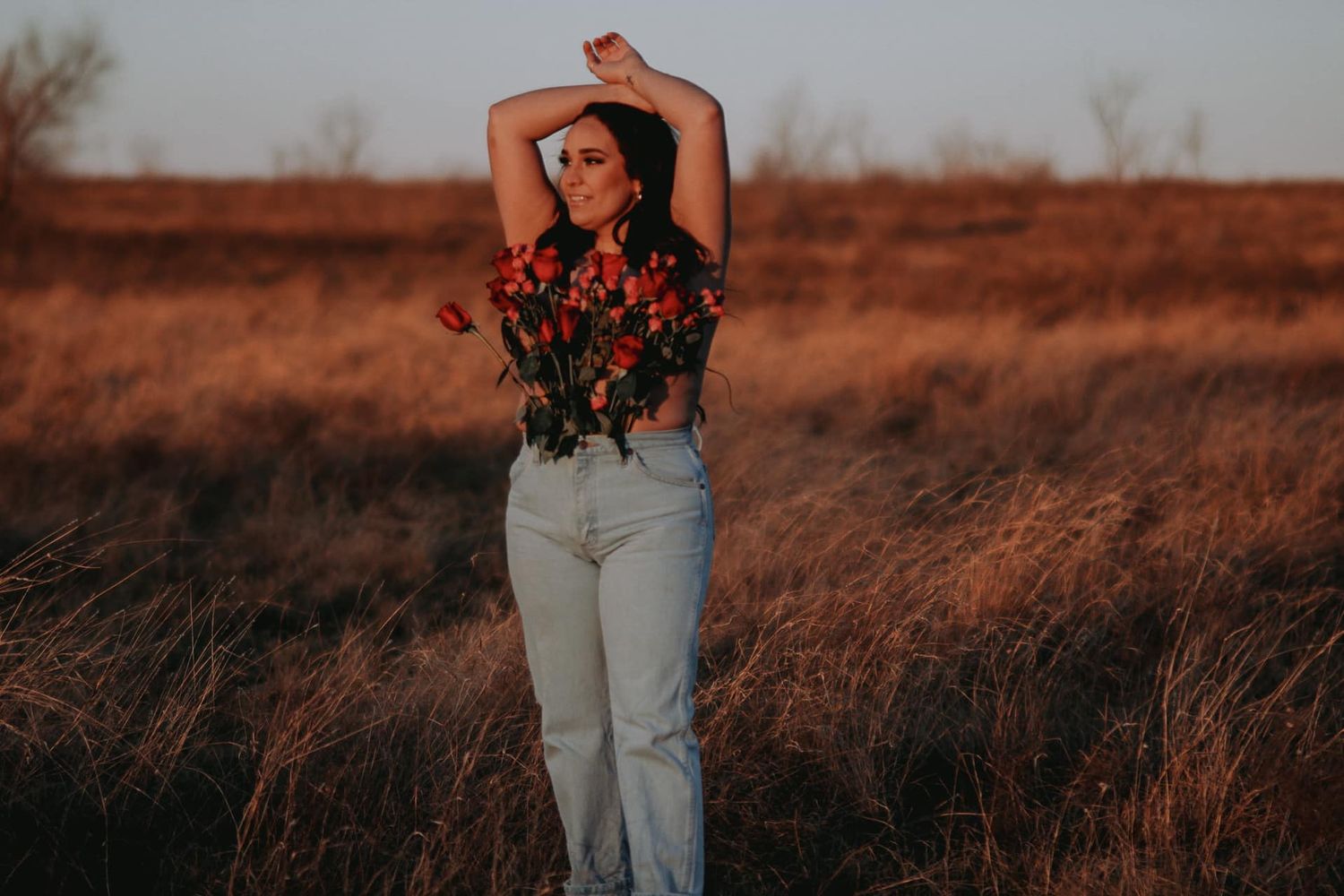 Artistic silhouette of someone posing in a field during golden hour.