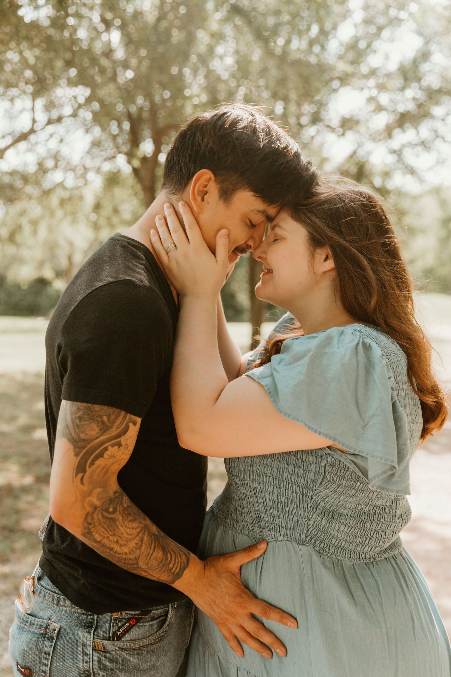 Intimate couple portrait outdoors showing affection with man's tattoo visible.
