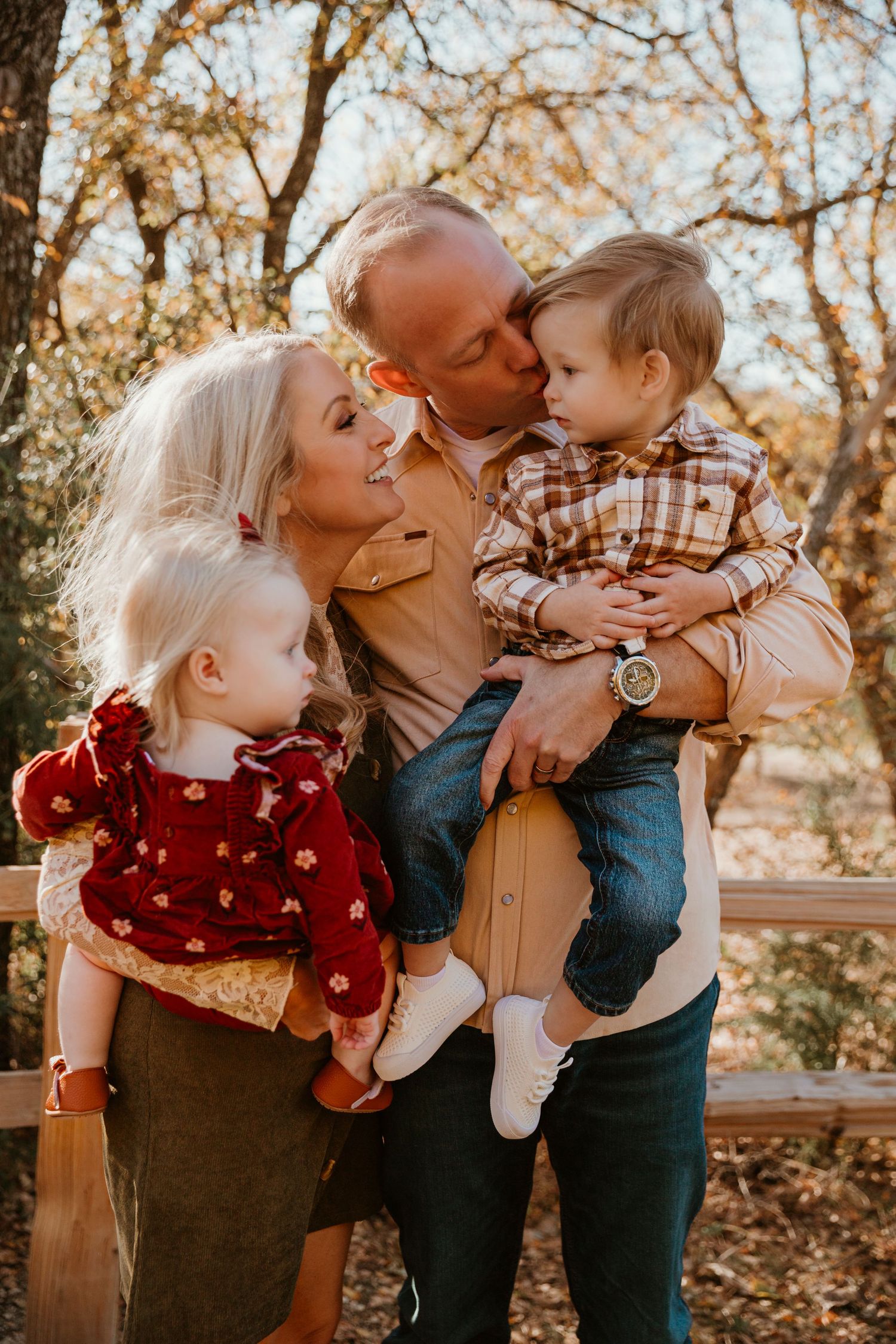 Warm autumn family photos show tender moments between parents and child amid golden fall foliage.