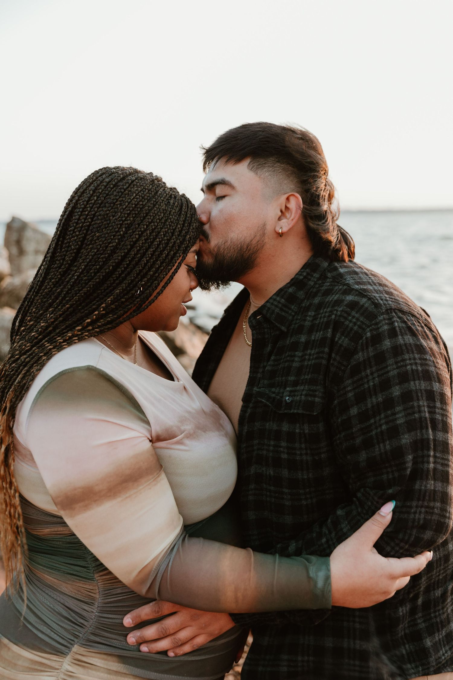 Romantic sunset moment between couple against ocean backdrop.