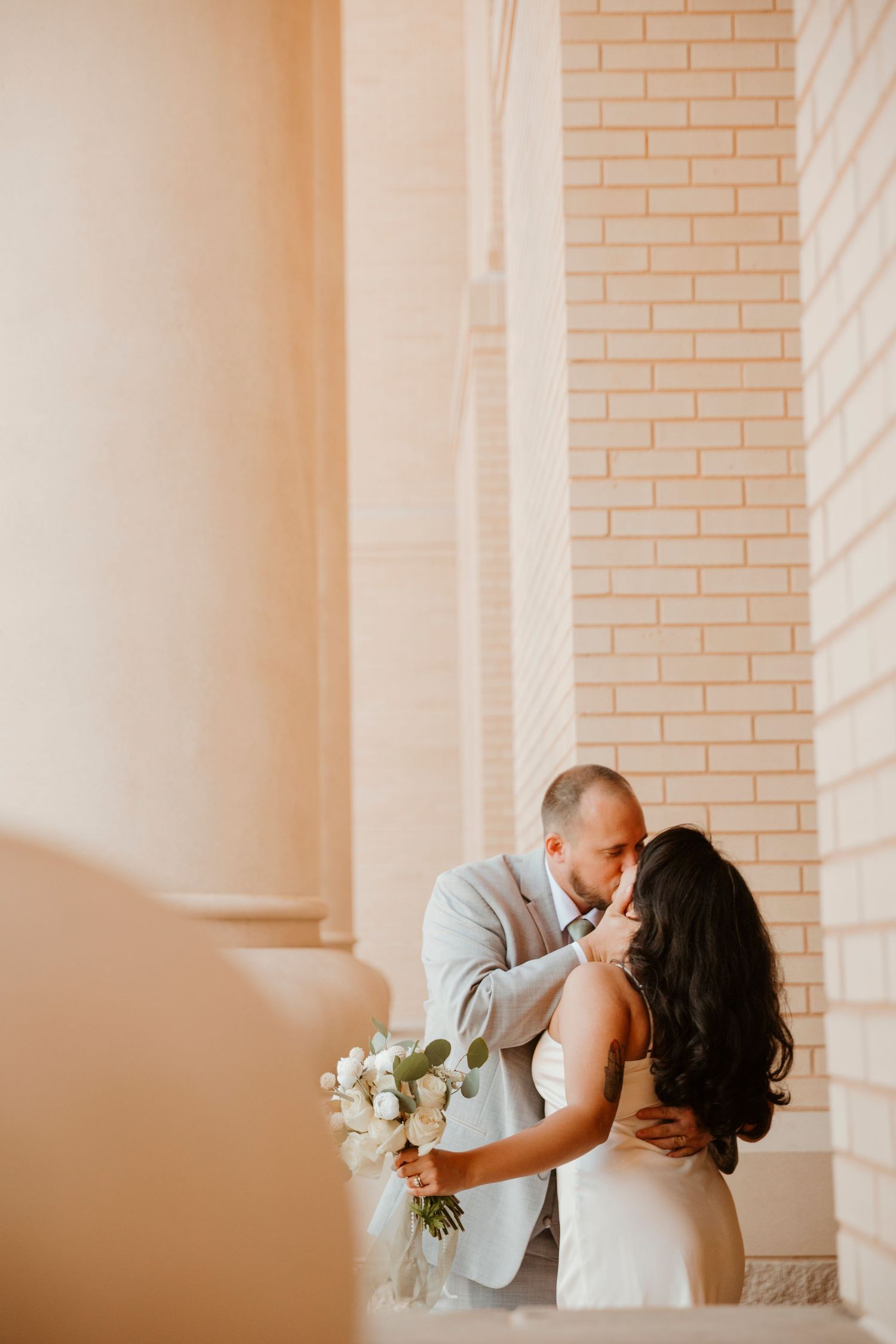 A romantic wedding sequence showing a couple sharing tender kisses against a light brick wall with soft lighting.