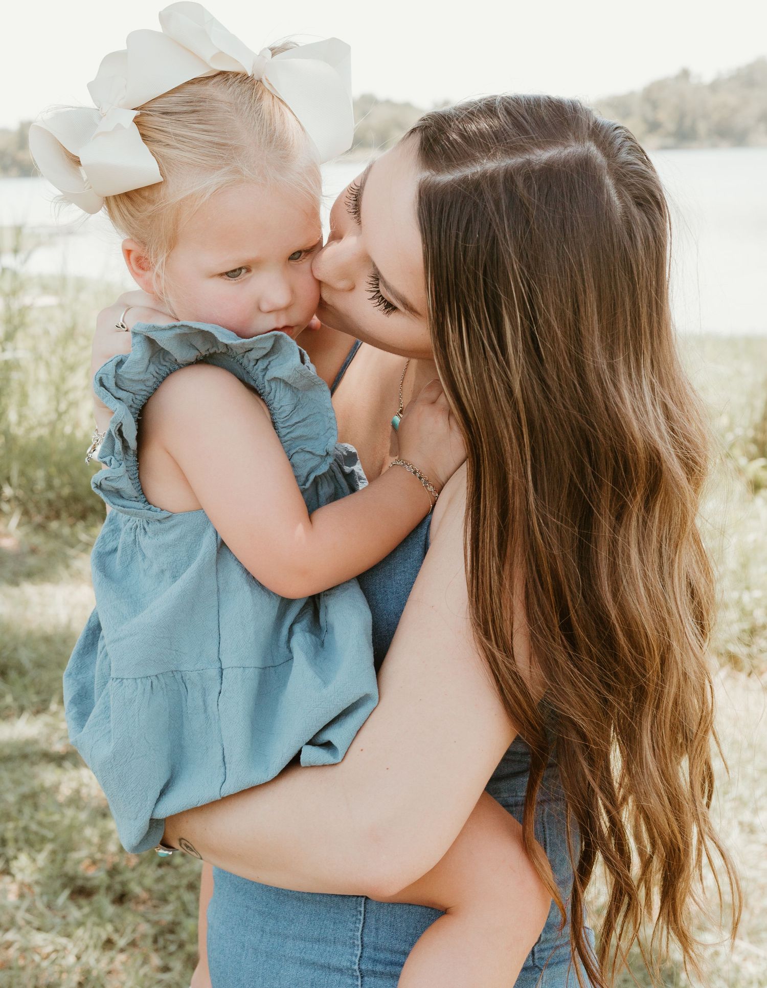Tender moment between parent and child outdoors in summer setting.