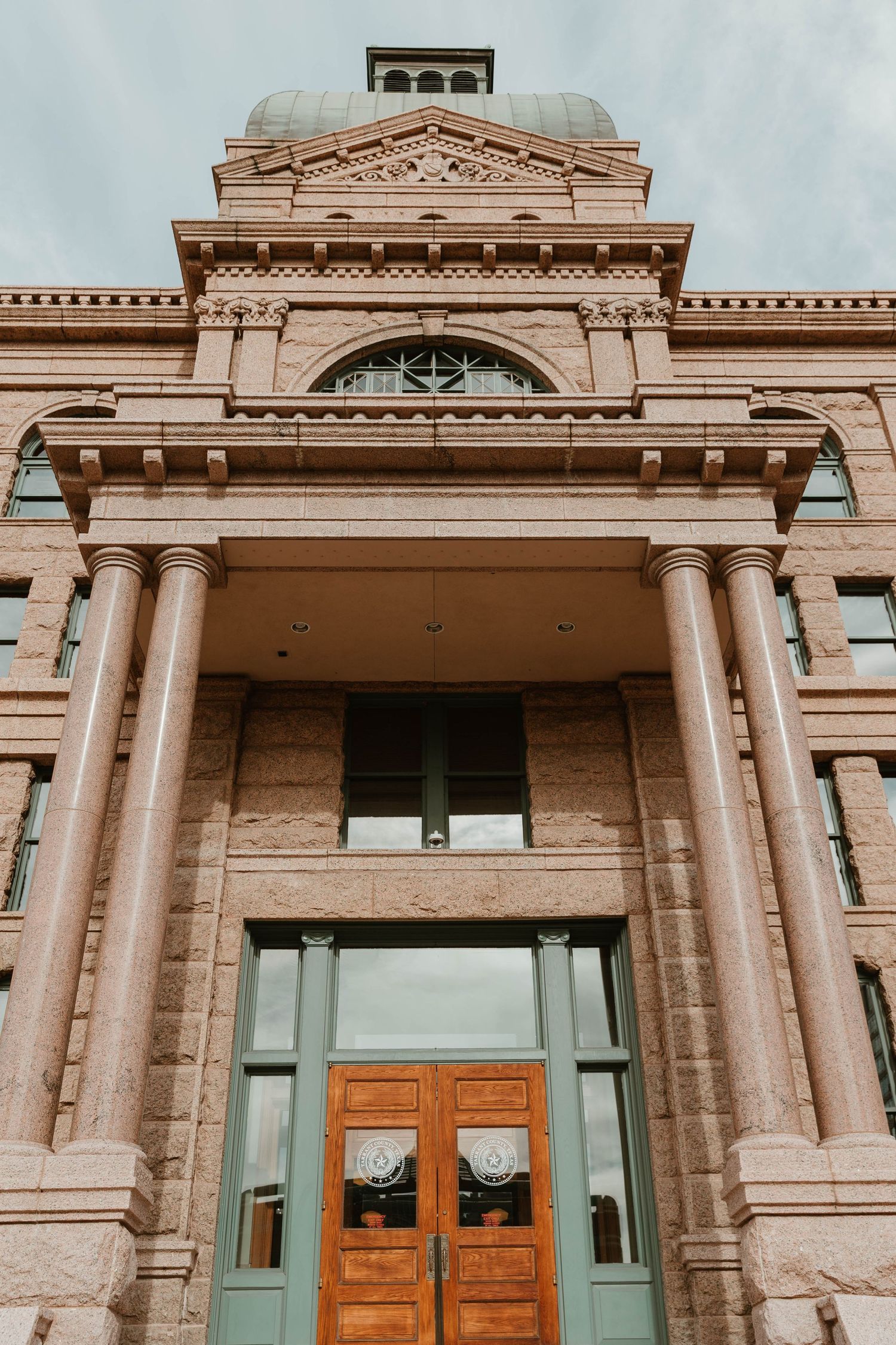 Neoclassical building facade with grand columns and wooden doors.