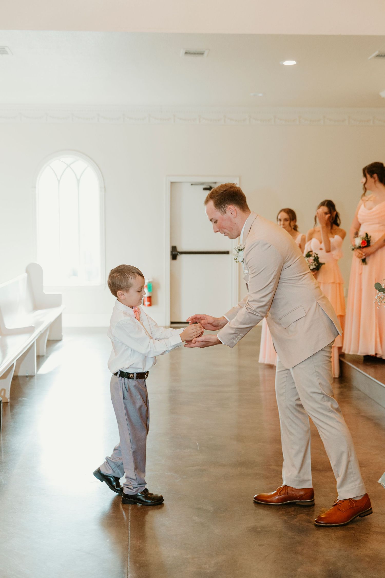A heartwarming sequence of a young boy greeting someone in formal attire in a bright indoor space.