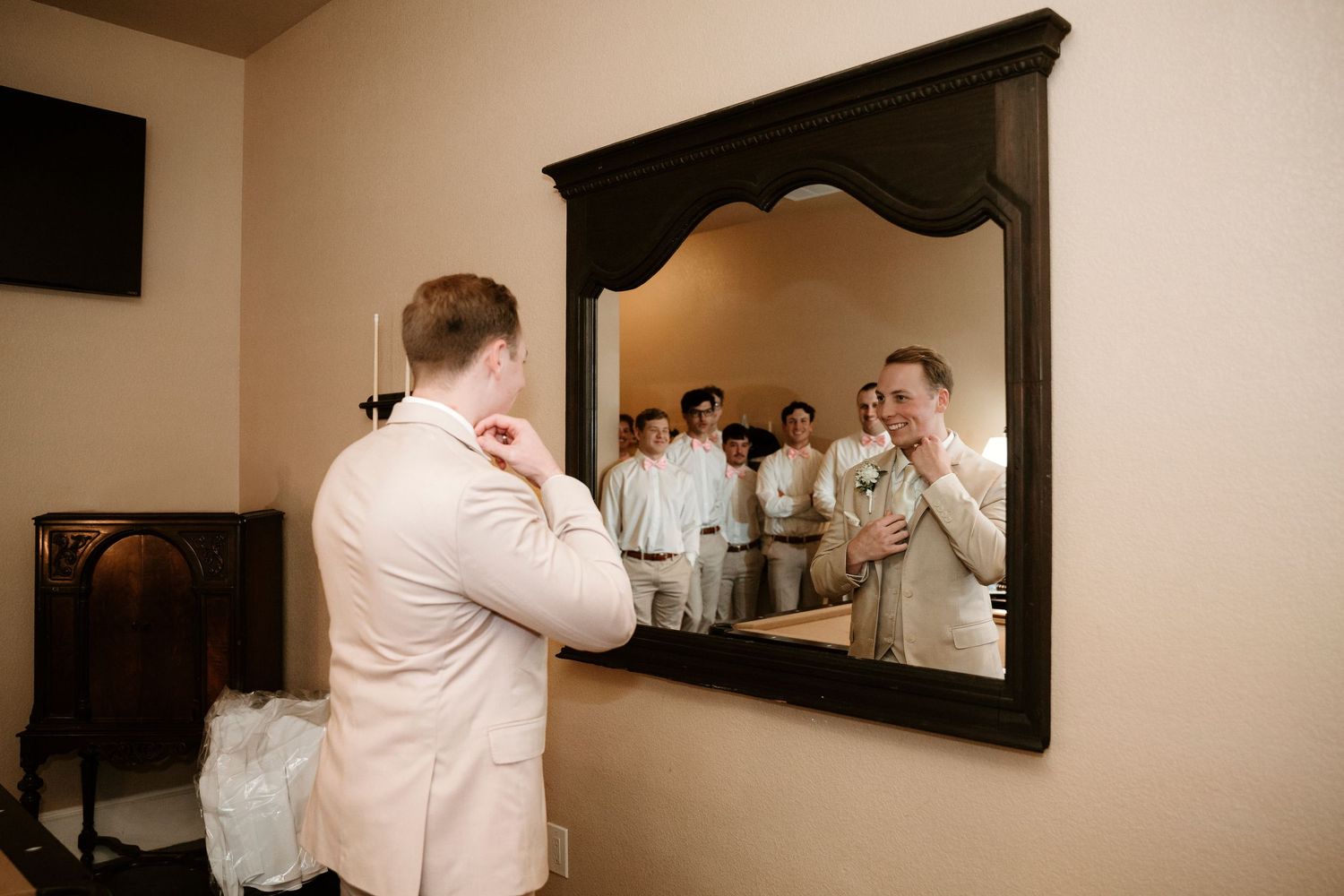 A series of five connected images showing someone putting on a white dress shirt and adjusting it in a mirror.