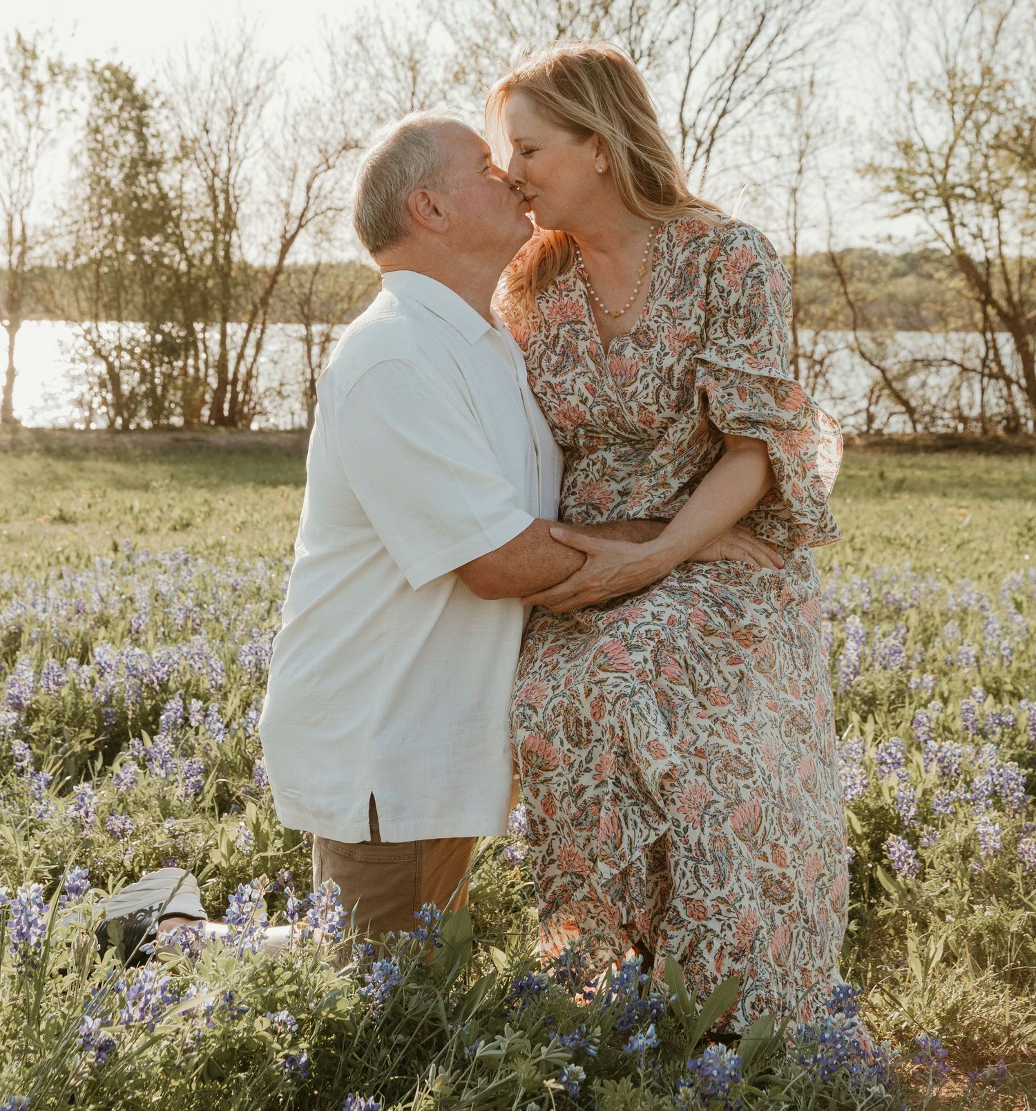 A couple shares an intimate moment in a wildflower field during golden hour.