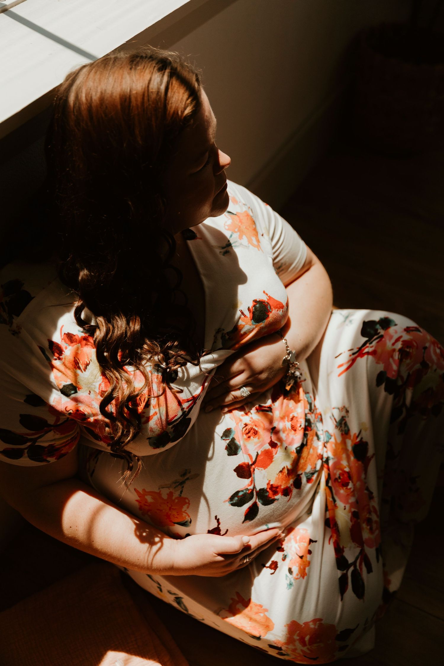 Person in floral dress photographed in dramatic lighting against dark background.