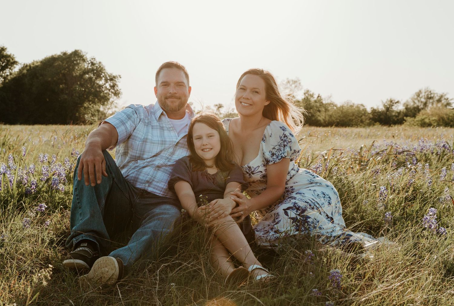 Family relaxing together in a wildflower meadow at sunset.