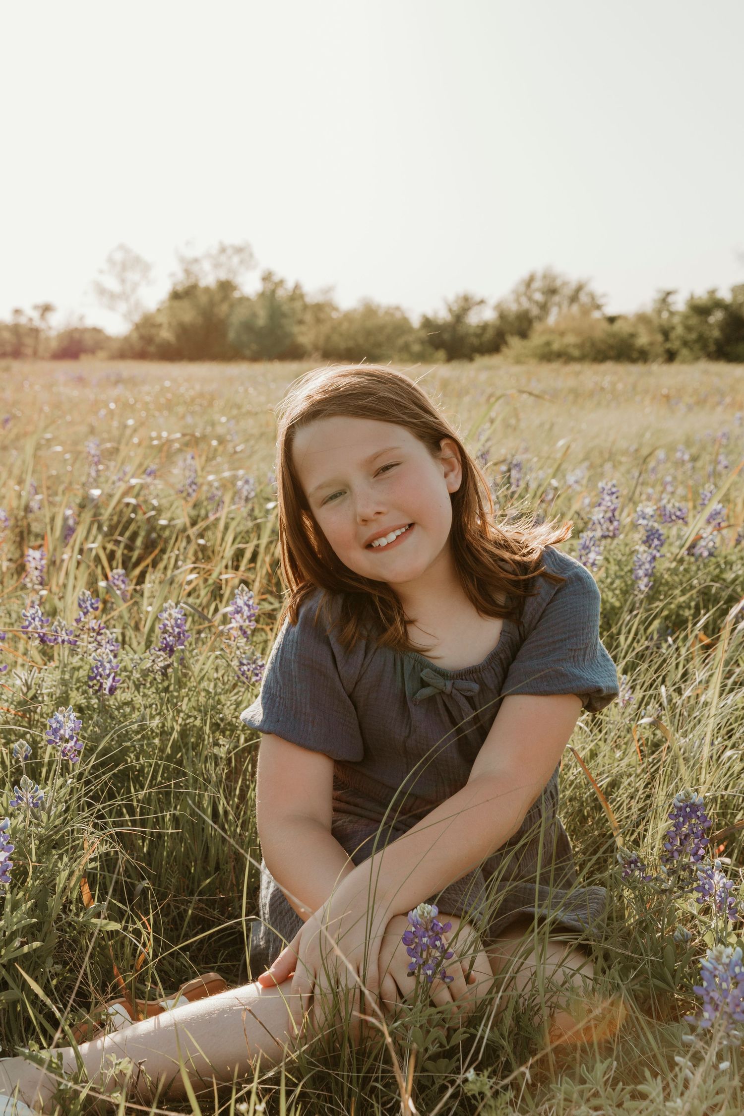 Natural sunlit portrait in field of purple wildflowers during golden hour.