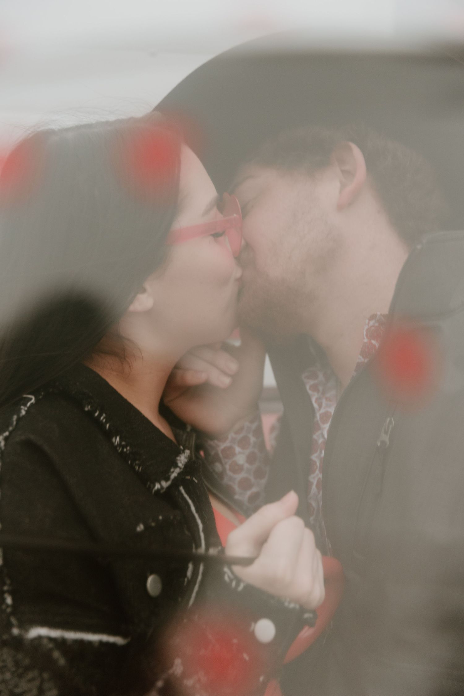 Romantic dreamy close-up photo of a couple kissing with soft red bokeh overlays.