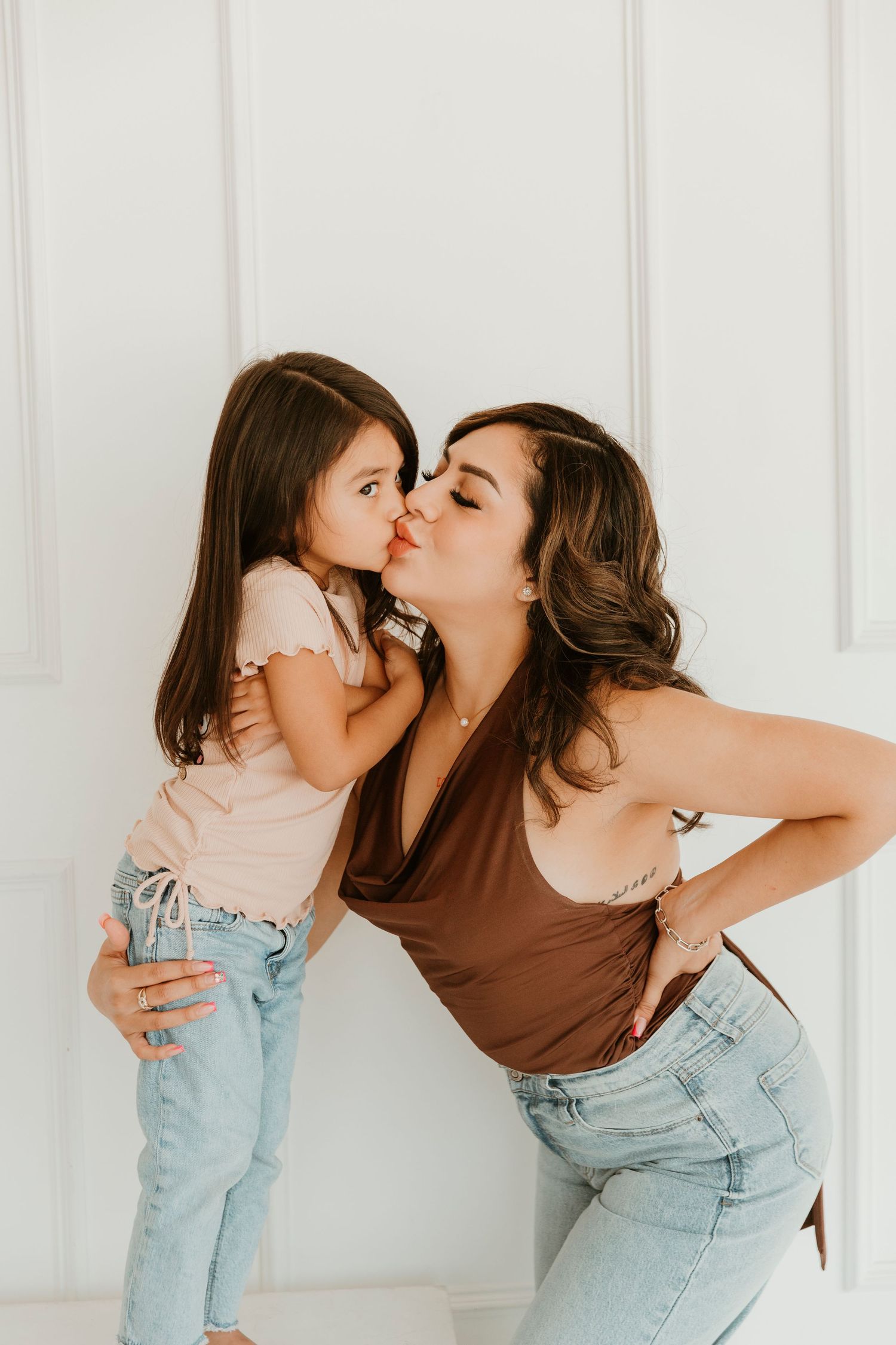Sweet moment between parent and child against white paneled wall.