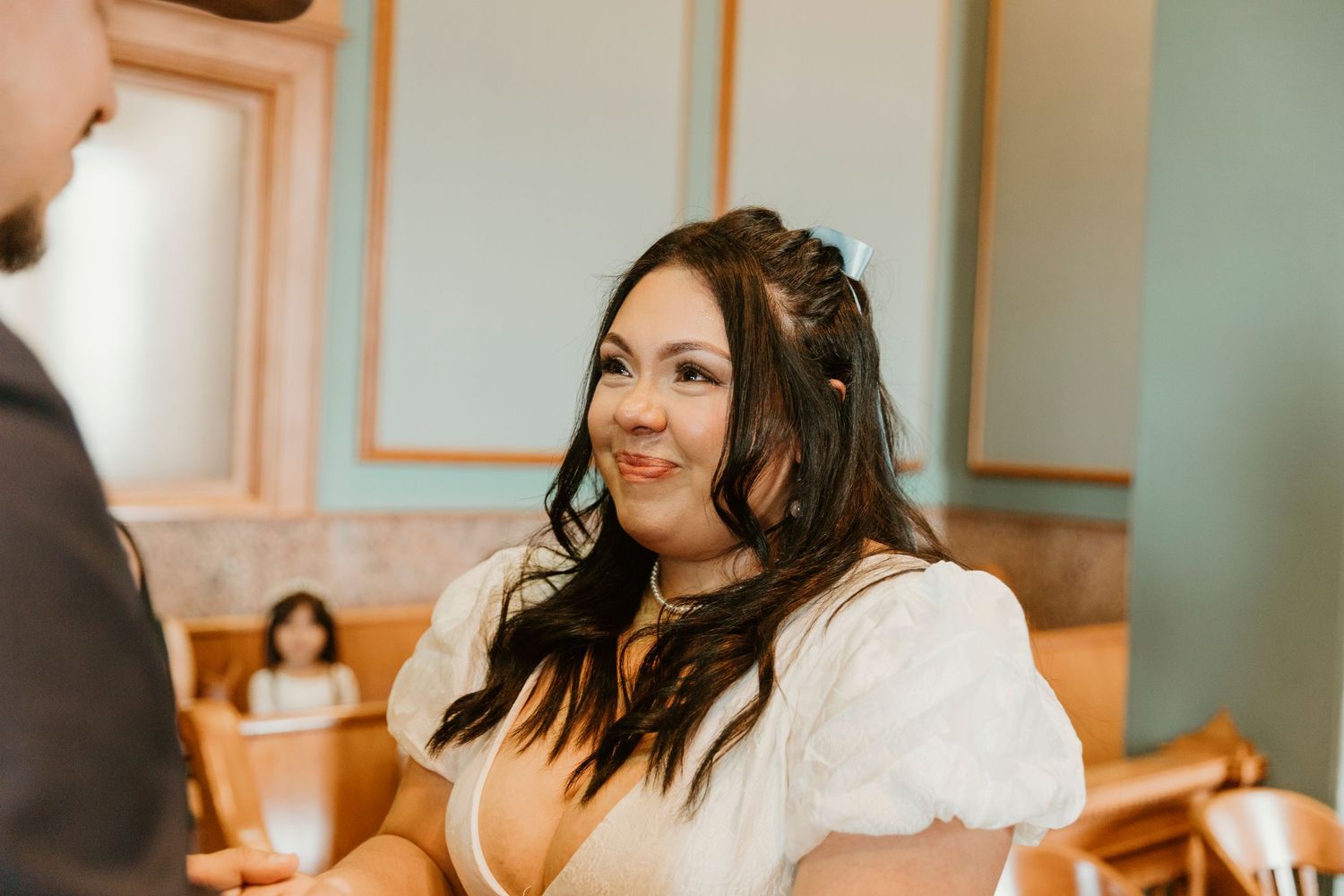 Wedding ceremony candid moment captured in a historic courthouse with mint green walls.