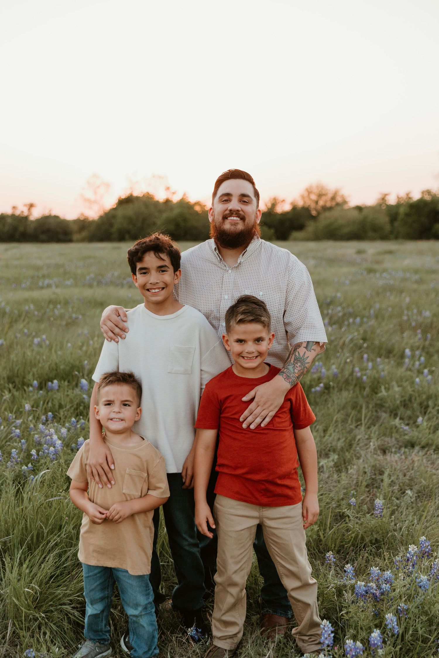Family portrait in a wildflower meadow at sunset with vibrant bluebonnets in bloom.