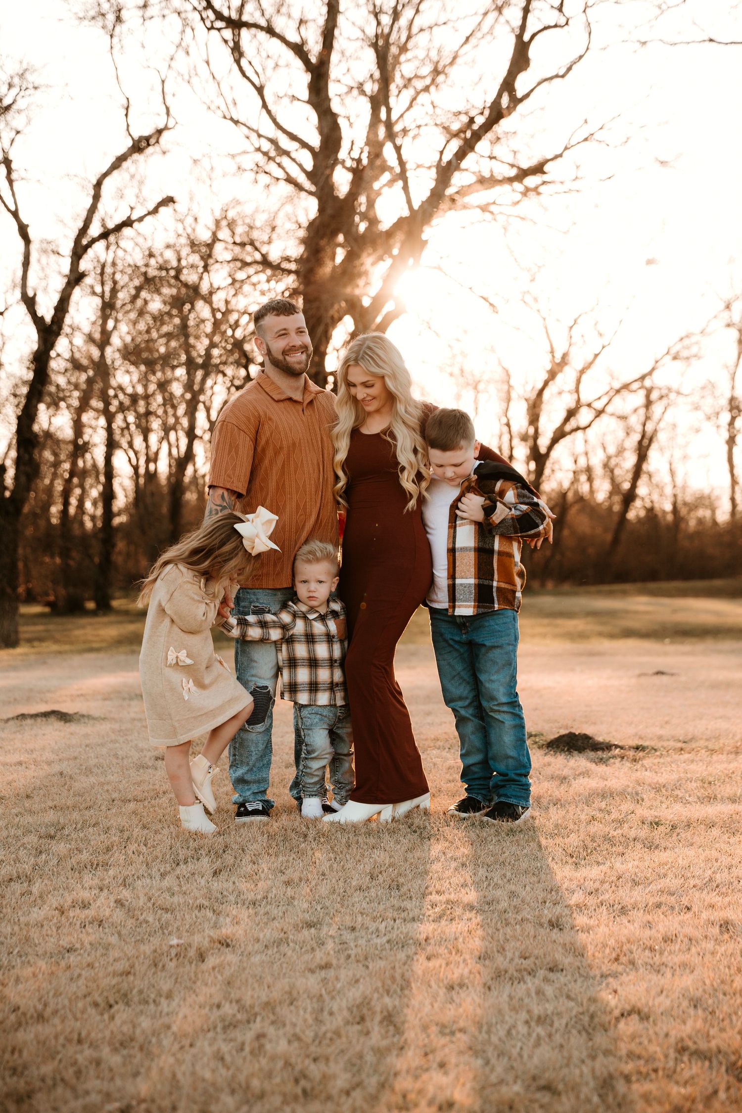 A family walks together through a sunlit field at golden hour holding a vintage lantern.
