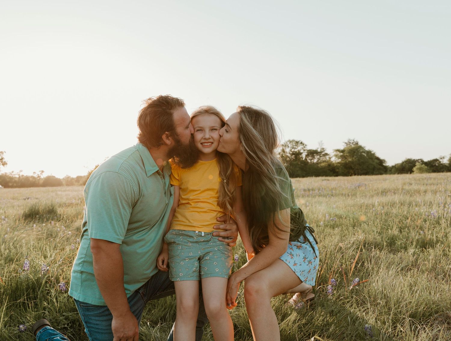 Family sharing tender moments in a sunlit meadow.